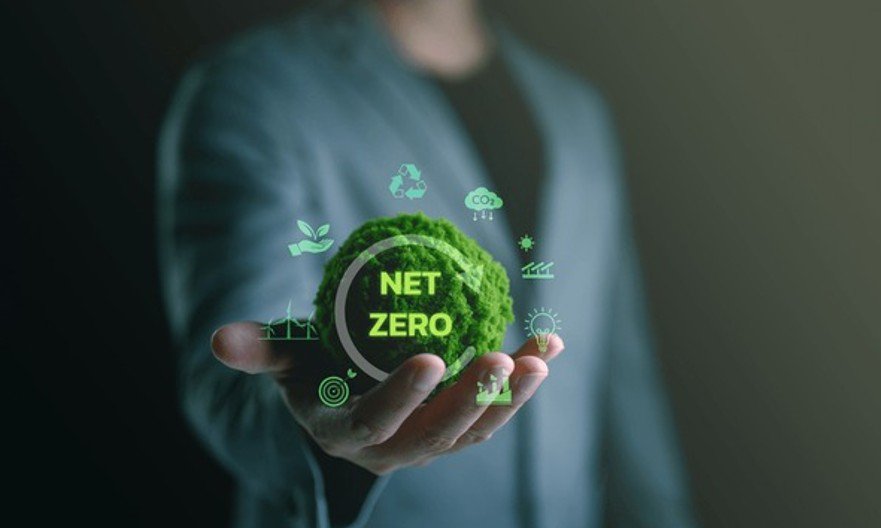 Person holding a net zero sustainability graphic with green energy and carbon reduction icons.